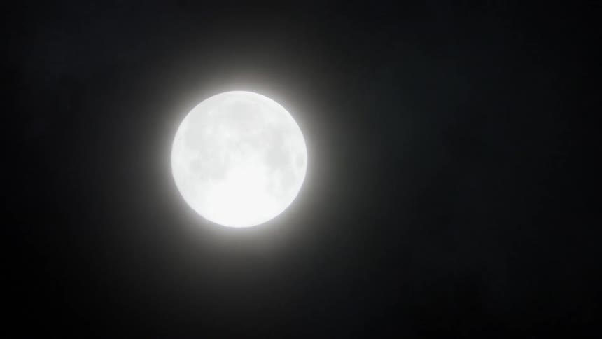 Mist floats in front of a full moon at night