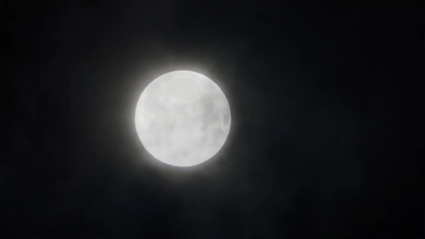 Clouds float in front of a full moon