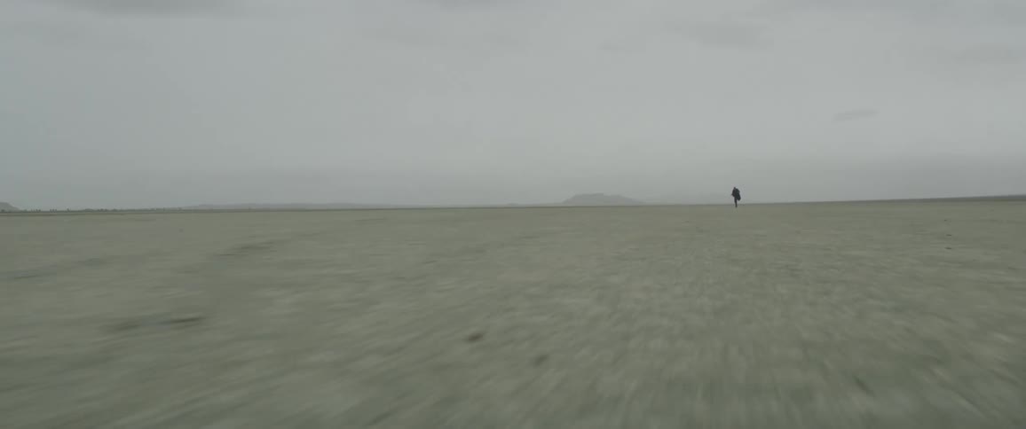 A man stumbles and runs across a dirt field
