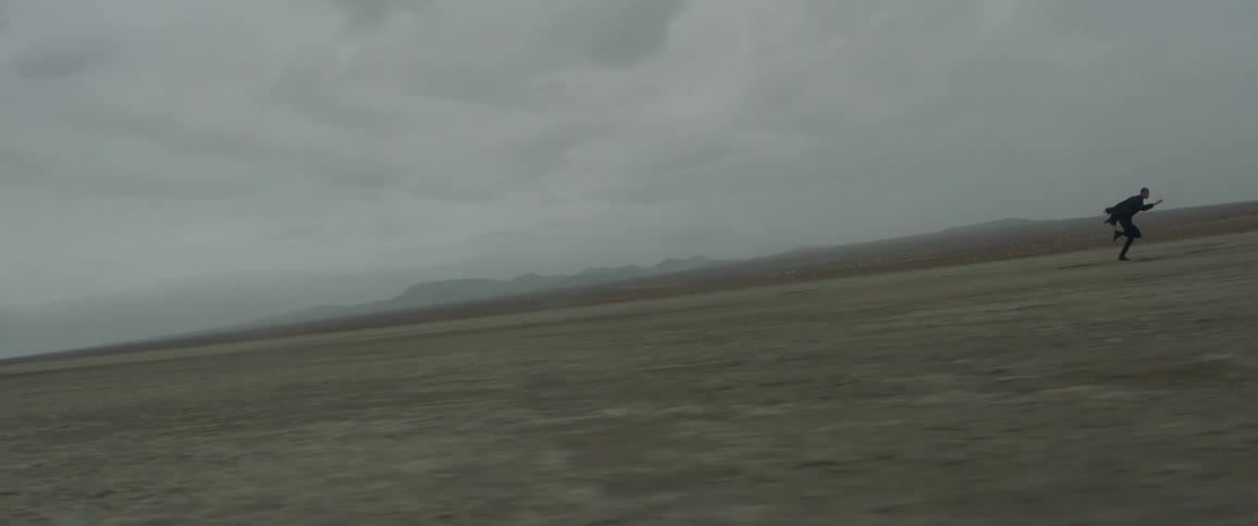 A man is running across the desert on a cloudy day