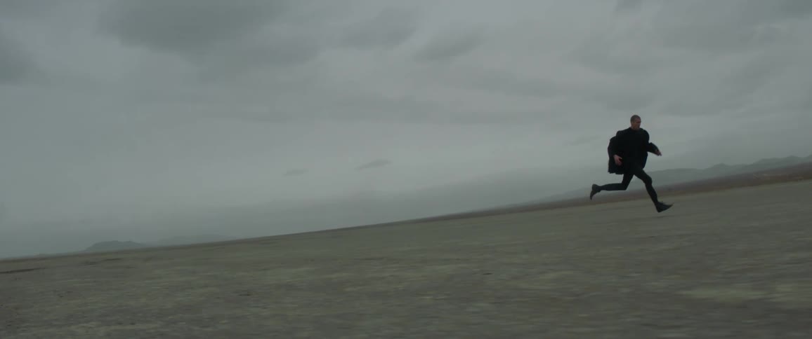 A man runs across an empty dirt field
