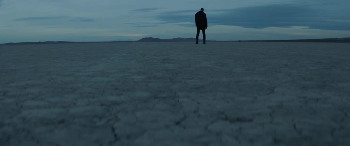 A man walks on the dry desert sand