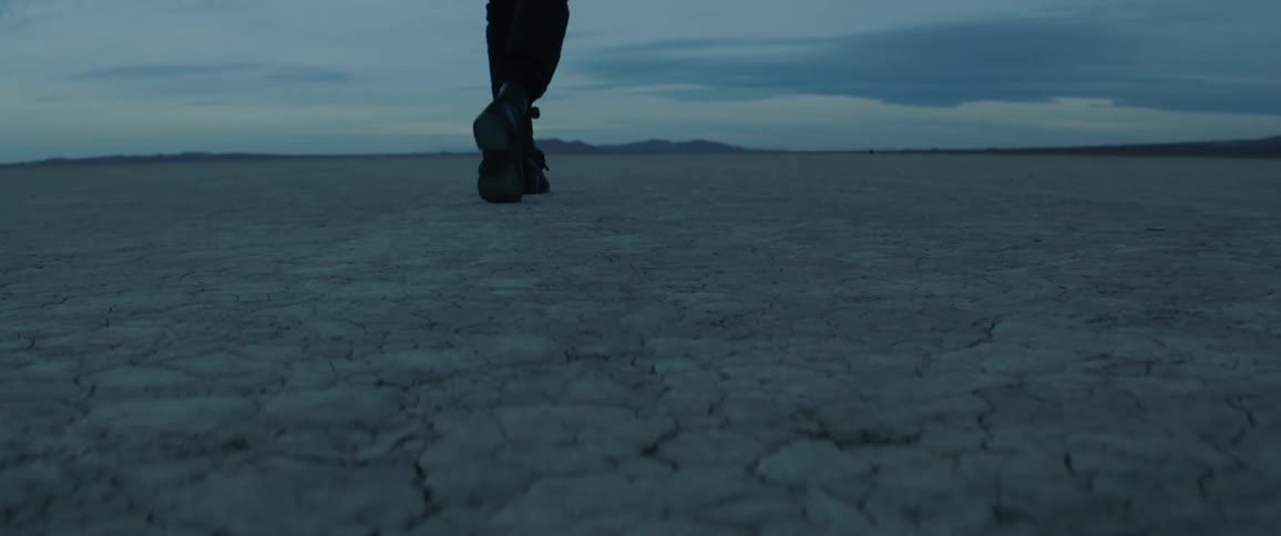 A man is walking in the desert at dusk