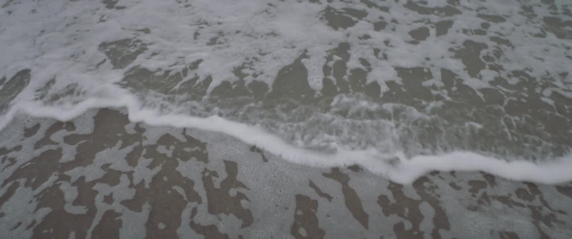 Waves roll in, disturbing the foamy water