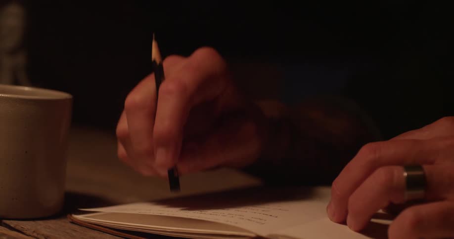A man tapping a pencil on a page of an open book