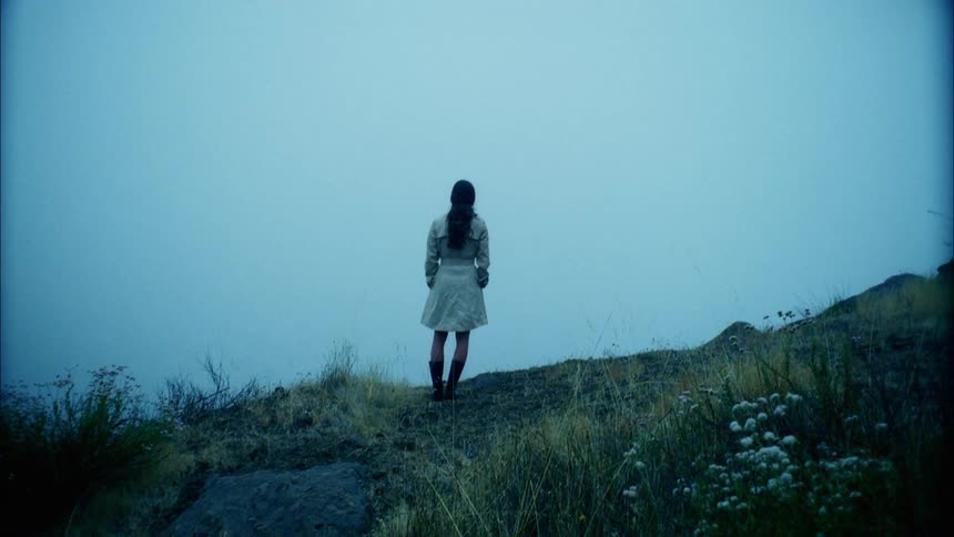 A woman standing on the edge of a cliff looking out