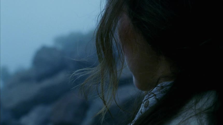 A woman is standing outdoors at dusk