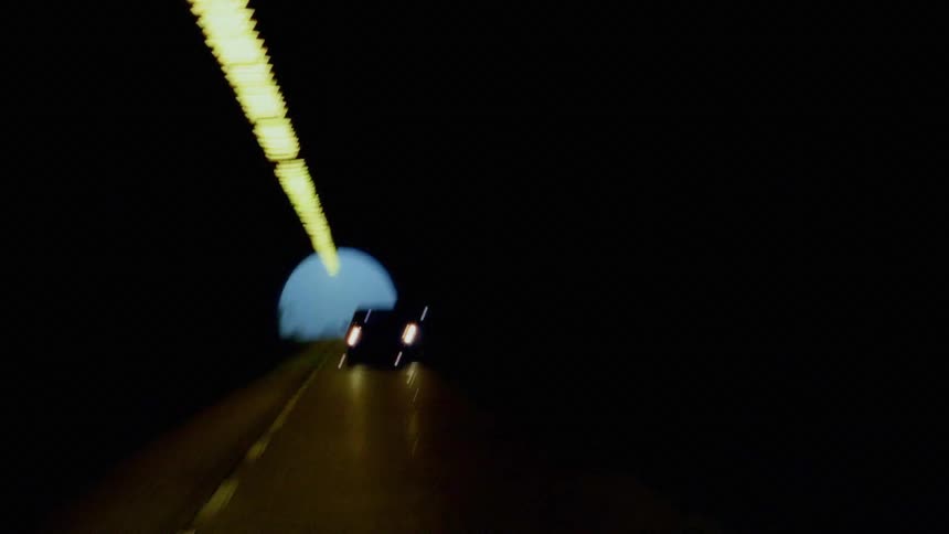 Cars with headlights on drive inside a dark tunnel after exiting to the fog outside