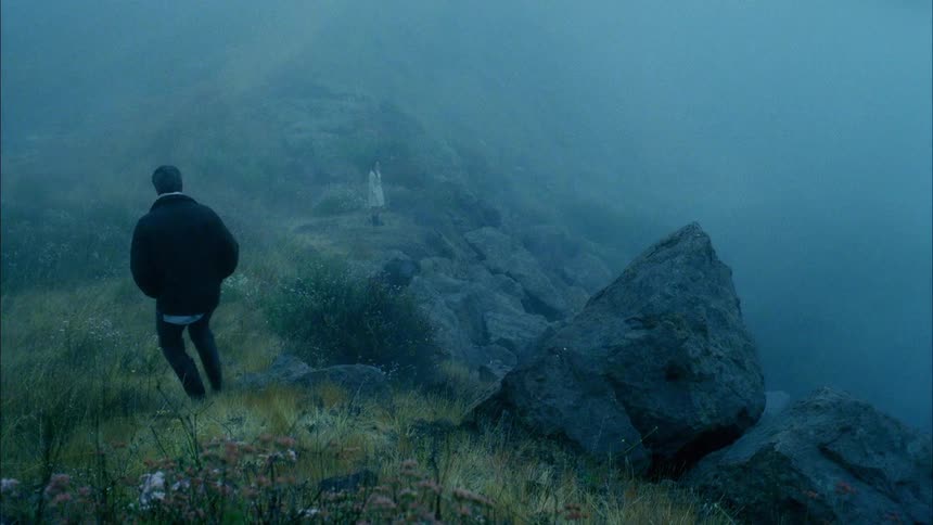 A man walks down a hill towards a woman