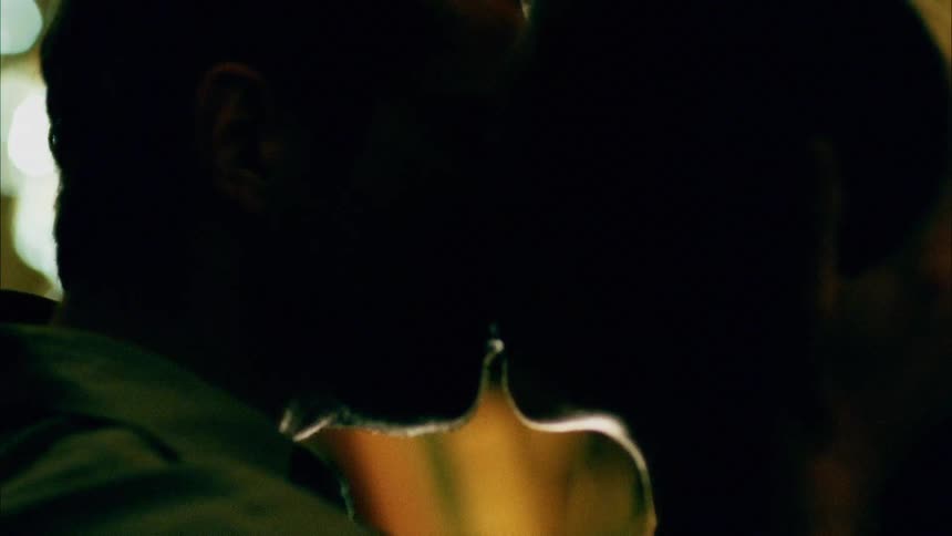 A man strokes a womans hair and then they kiss