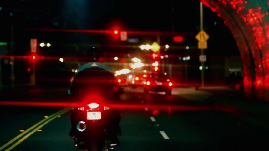 Cars and a motorcycle driving through a tunnel with people sitting inside of it