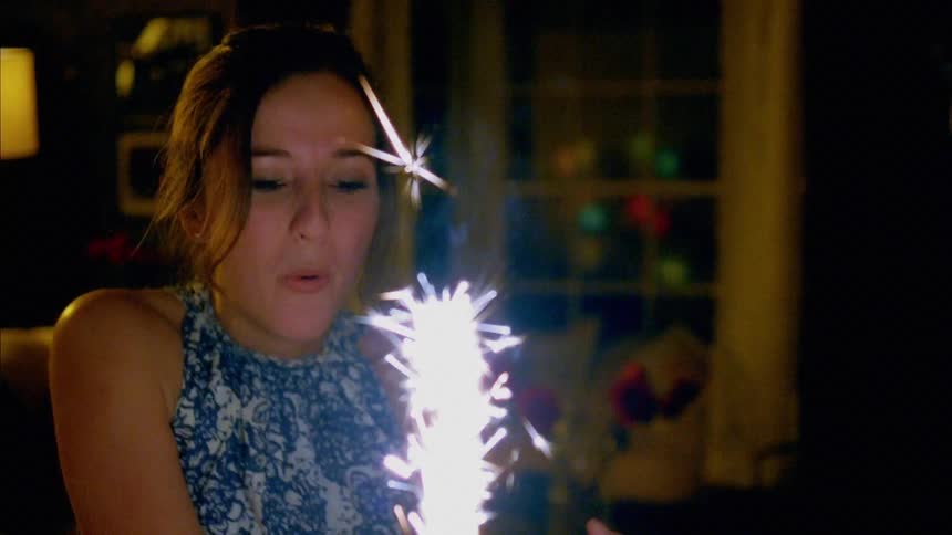 Young couple celebrate birthday with a cake in their home at night