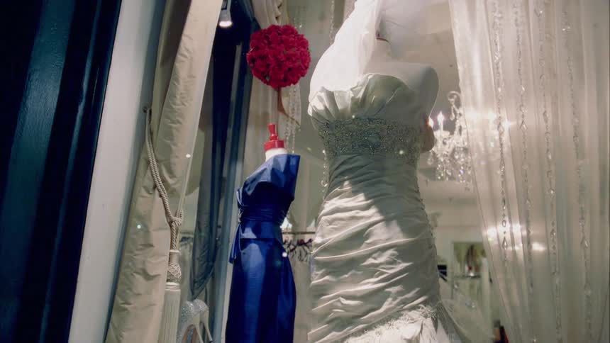 Formal gowns in the window of a clothing shop at night