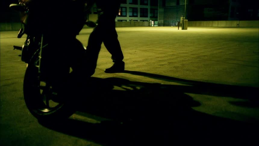 A person is getting on a motorcycle at night