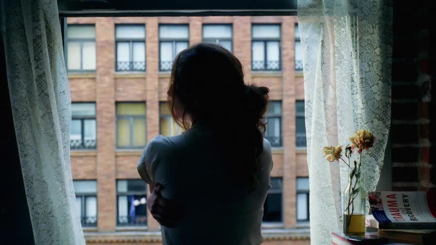A woman looks out her apartment window