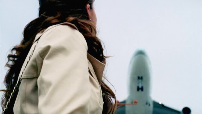 A woman looks up at a flying plane