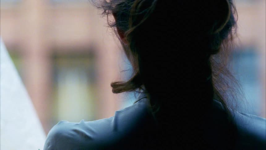 A female caucasian standing still with wind blowing in her hair
