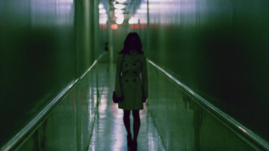 A young woman walking down a dimly lit corridor