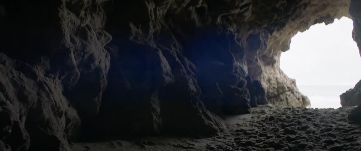 The sun shines into a cave and highlights the stone walls