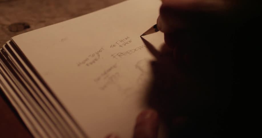 Person writing and drawing a picture in a book in pencil
