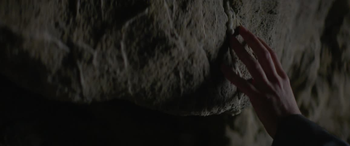A person's hand touches a rock