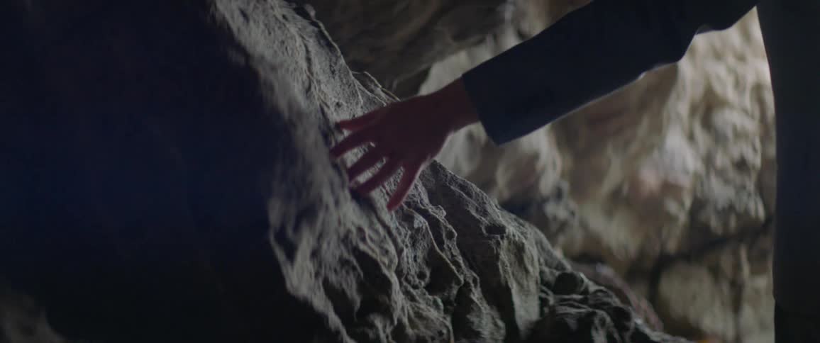 A man traces his hand across the stone cave