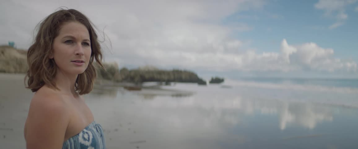 A woman stands on a sandy beach