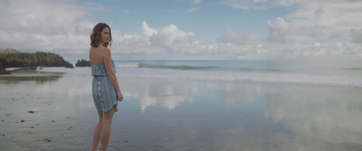 A woman stands on a sandy beach