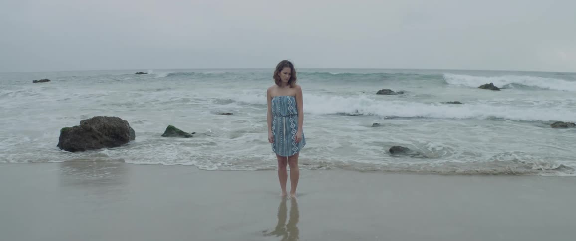 Woman looks down standing in the ocean
