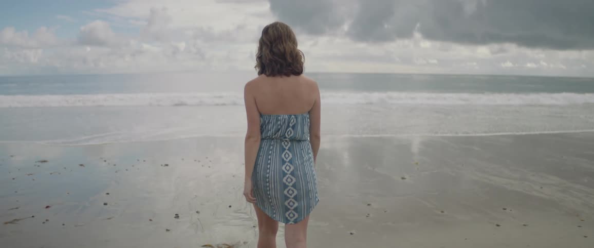A woman walks on a sandy beach