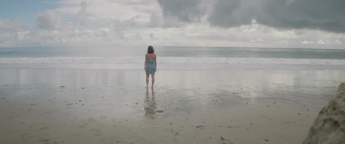 A woman stands still on the beach
