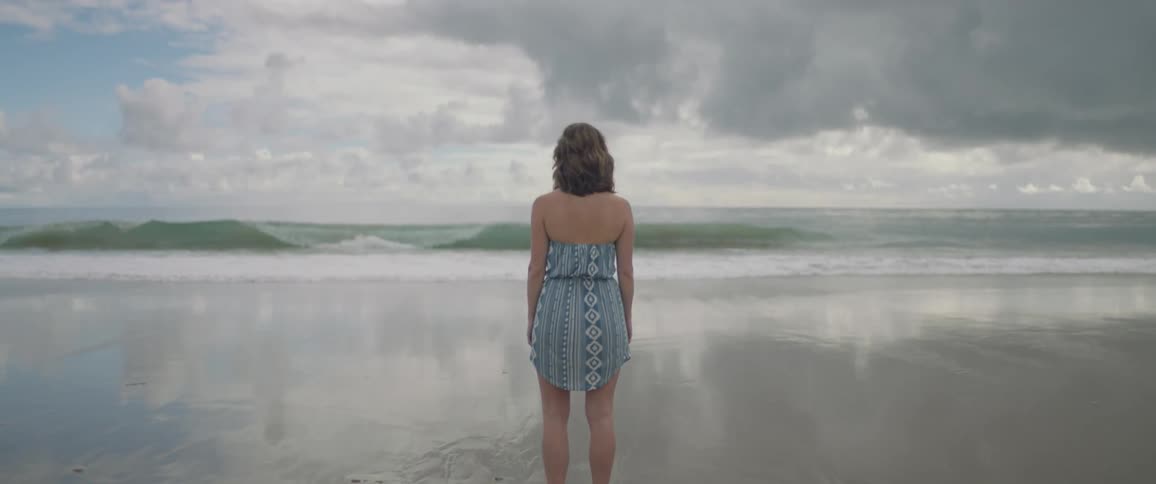 A woman stands on a sandy beach