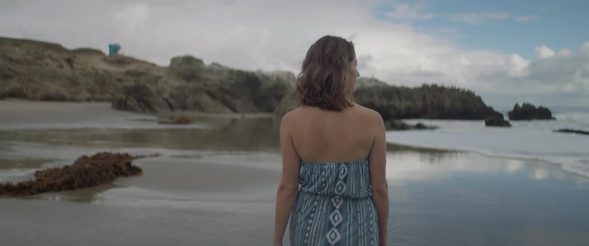 A woman walks on a sandy beach