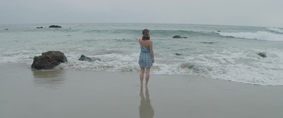 Woman stands at the shore while waves roll in