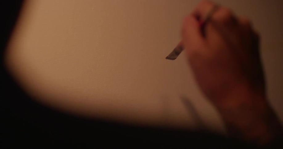 A trembling hand holds a paintbrush over a canvas