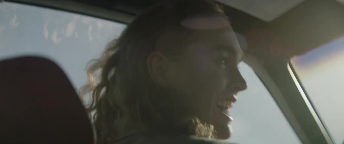 Person smiles and rides in a car on a sunny day