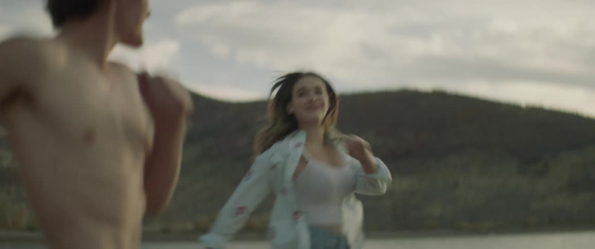 Couple running on a shore and then coming to a stop on a cloudy day