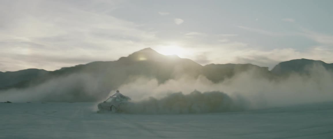 Person rides on the roof of a car that is turning in circles causing dust to rise up
