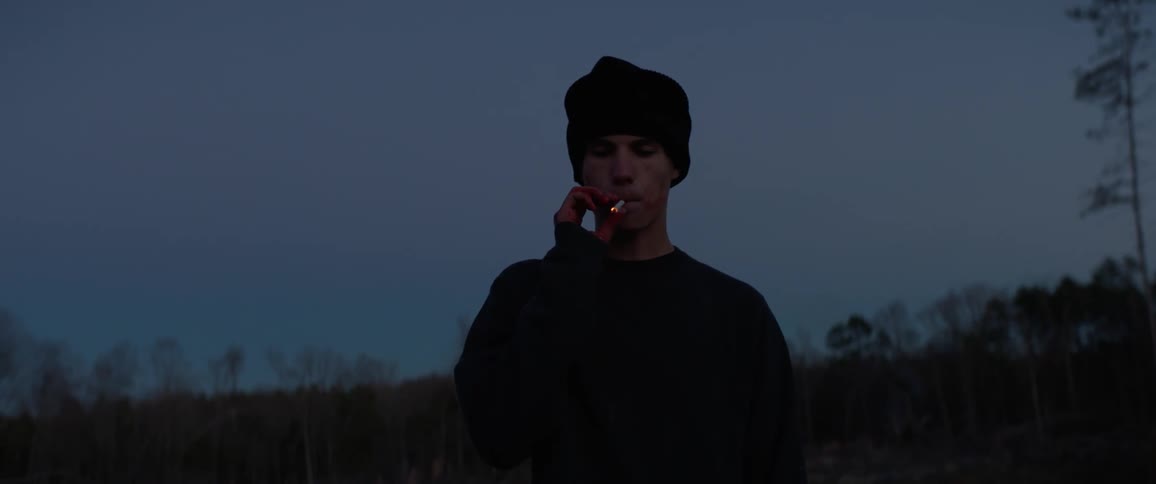 A young man with blood on his hands is smoking