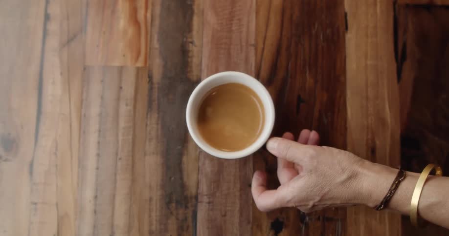 A person is putting a coffee cup on a table