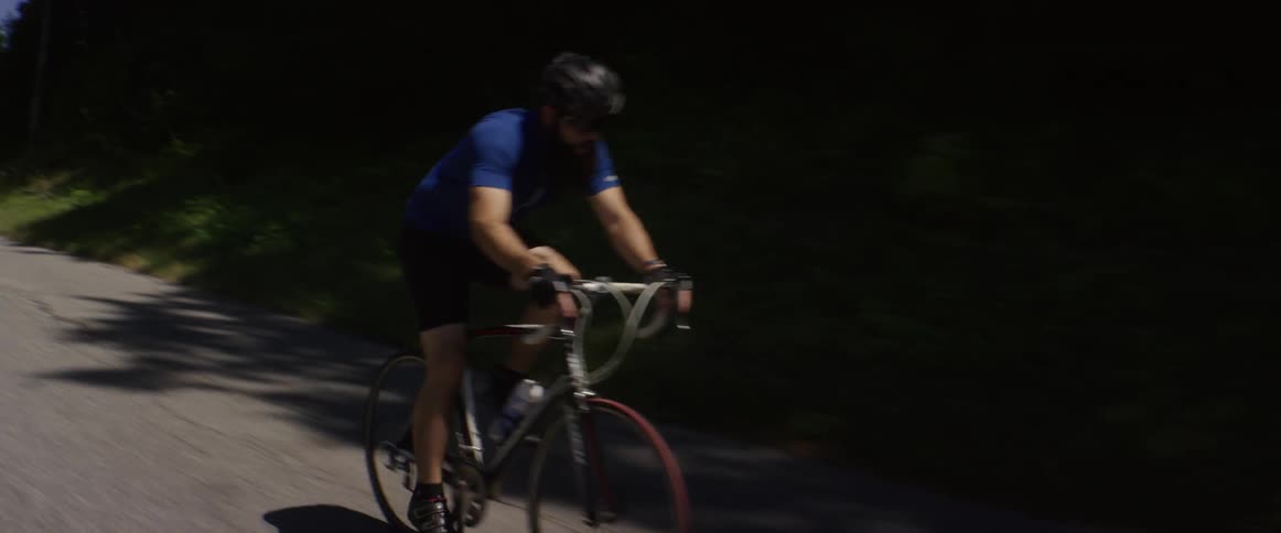 A man is racing downhill on a road on a bicycle