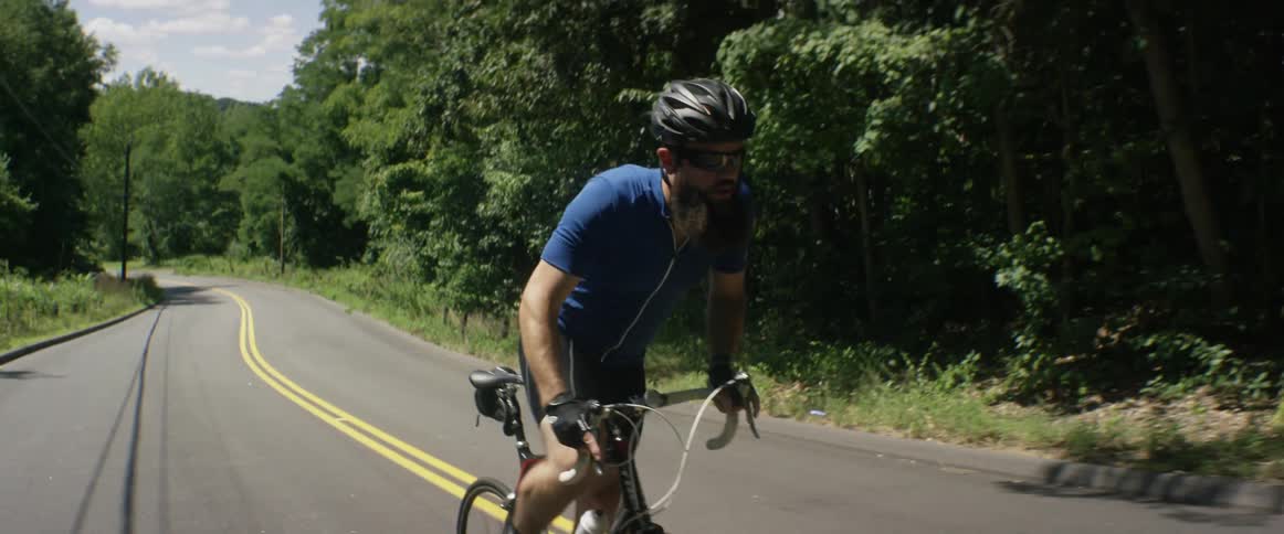 A man bicycles down a rural road on a sunny day