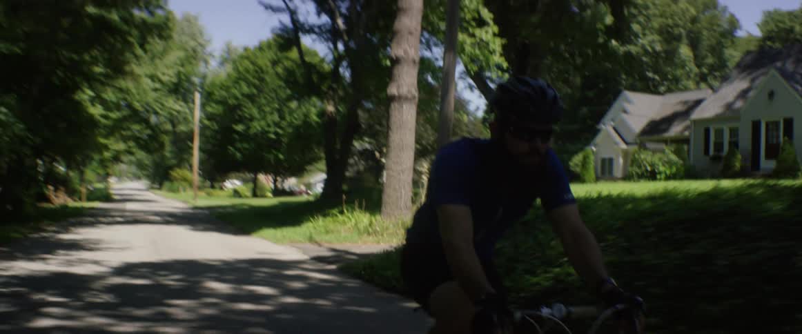 A man bicycles down a rural road on a sunny day