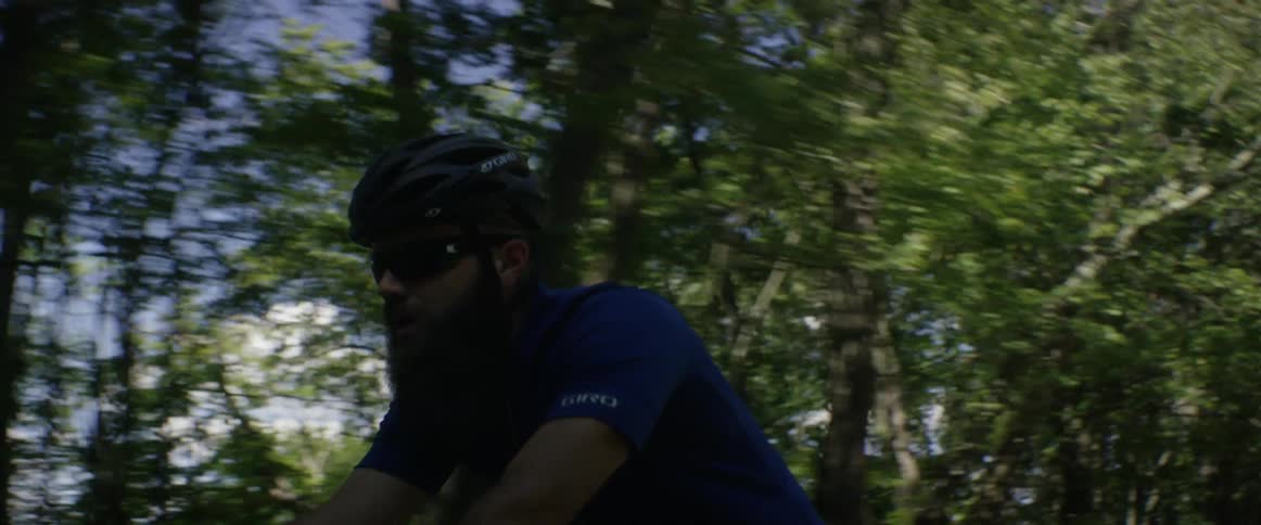 A bicyclist pedals in a wooded area