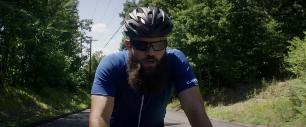 A man riding a bicycle along a tree-lined rural road