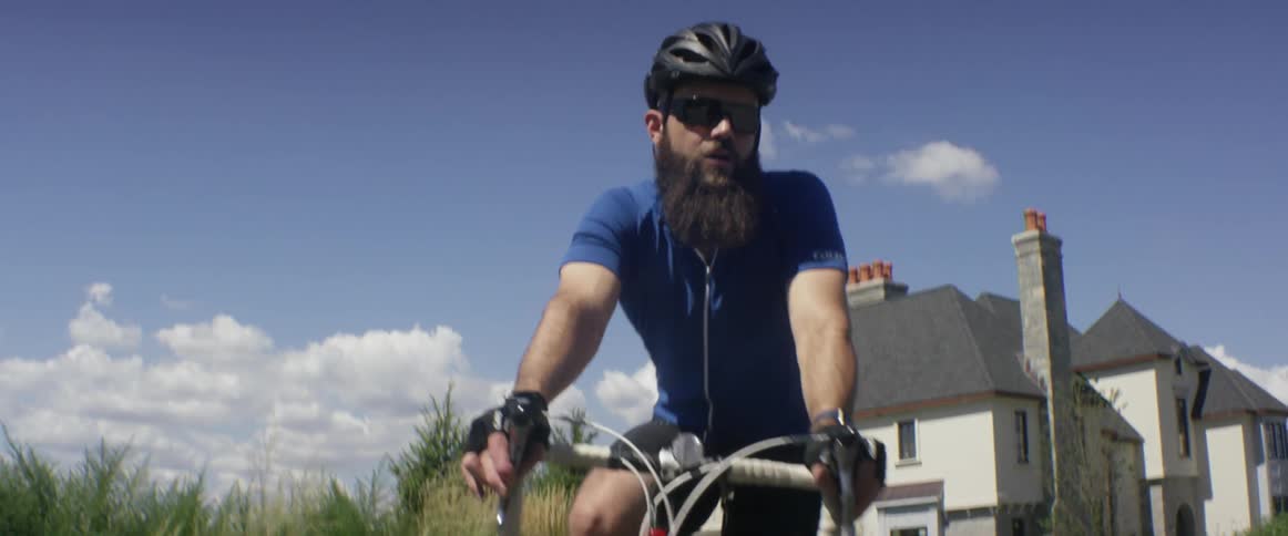 A bicyclist rides in front of a house on a sunny day