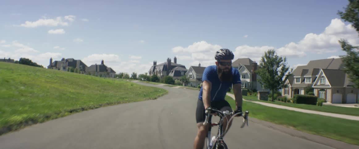 A man is riding his bike down a residential road