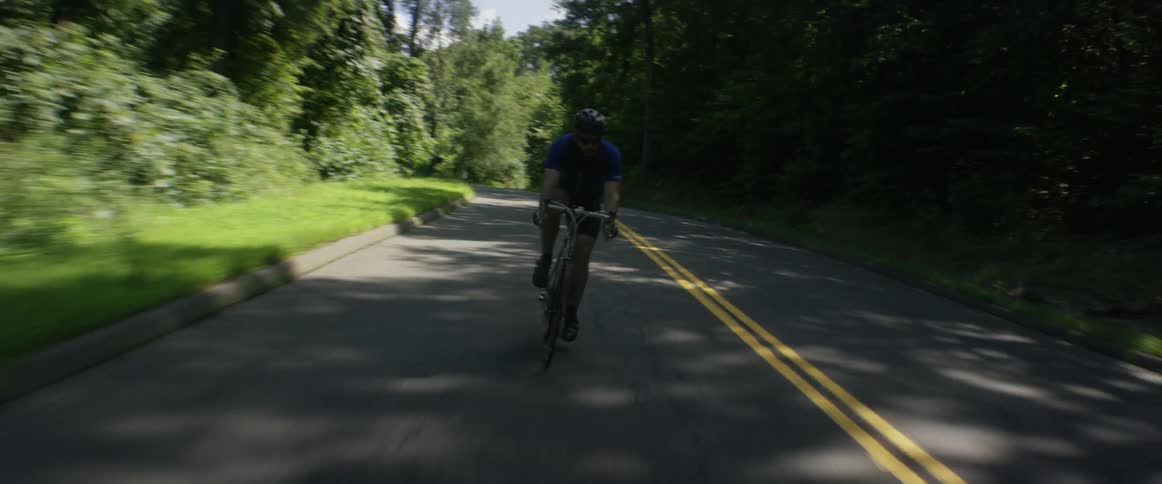A man riding a bicycle on a road in the day time