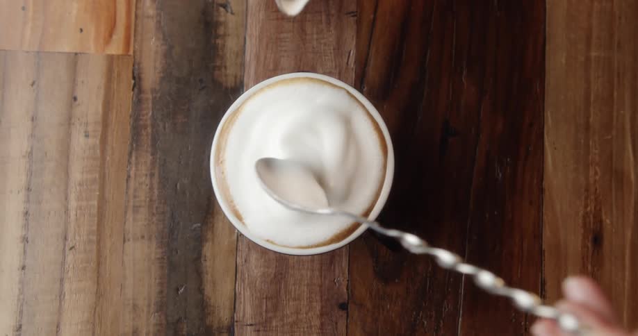 A woman putting foam on top of a coffee in a restaurant