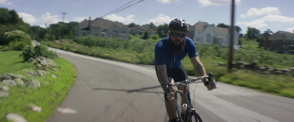 A man riding a bicycle on a two lane rural road